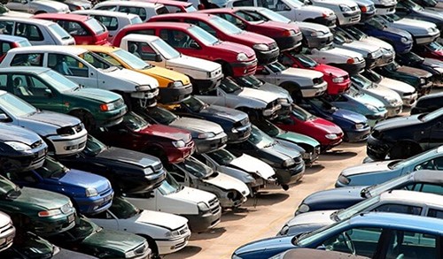 Large rows of stacked scrap cars and salvaged vehicles at an automotive recycling facility