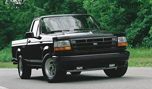 Black Ford F-150 SVT Lightning truck on a rural road.