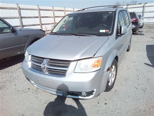 Silver Dodge Grand Caravan parked on a salvage dirt lot.